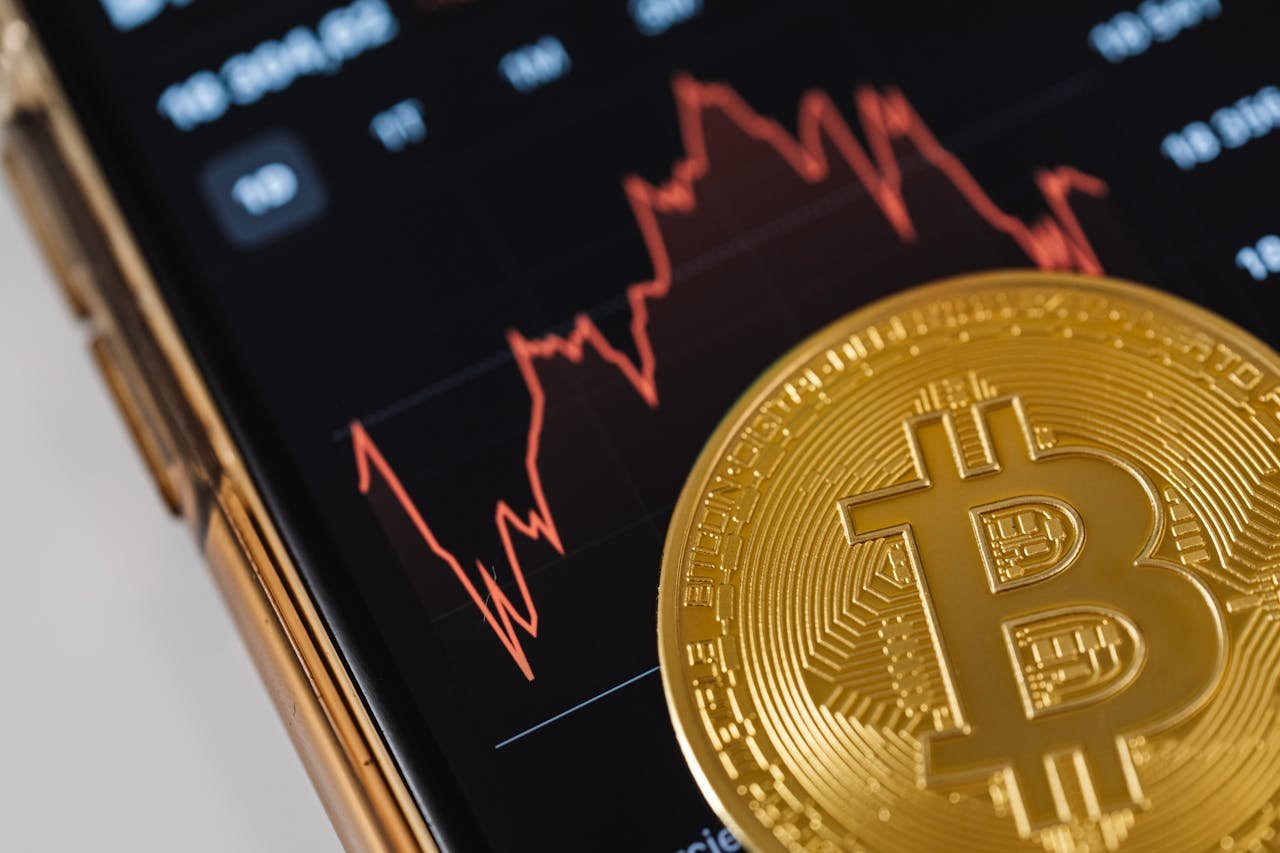 Close-up of a Bitcoin Coin Lying on a Screen Displaying a Stock Market Chart